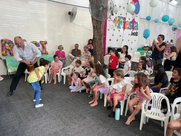 El mago juega con un niño voluntario ante una fila de niñas riendo