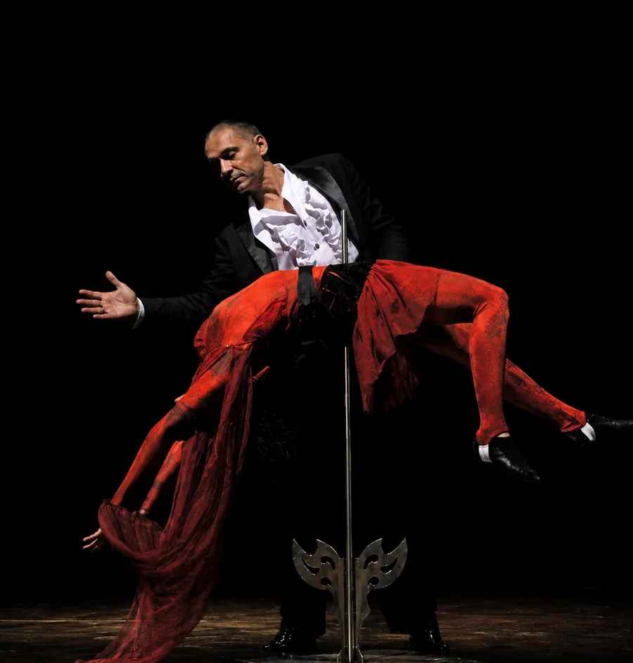 El mago sostiene en el aire a una artista vestida de rojo en un acto de gran ilusión
