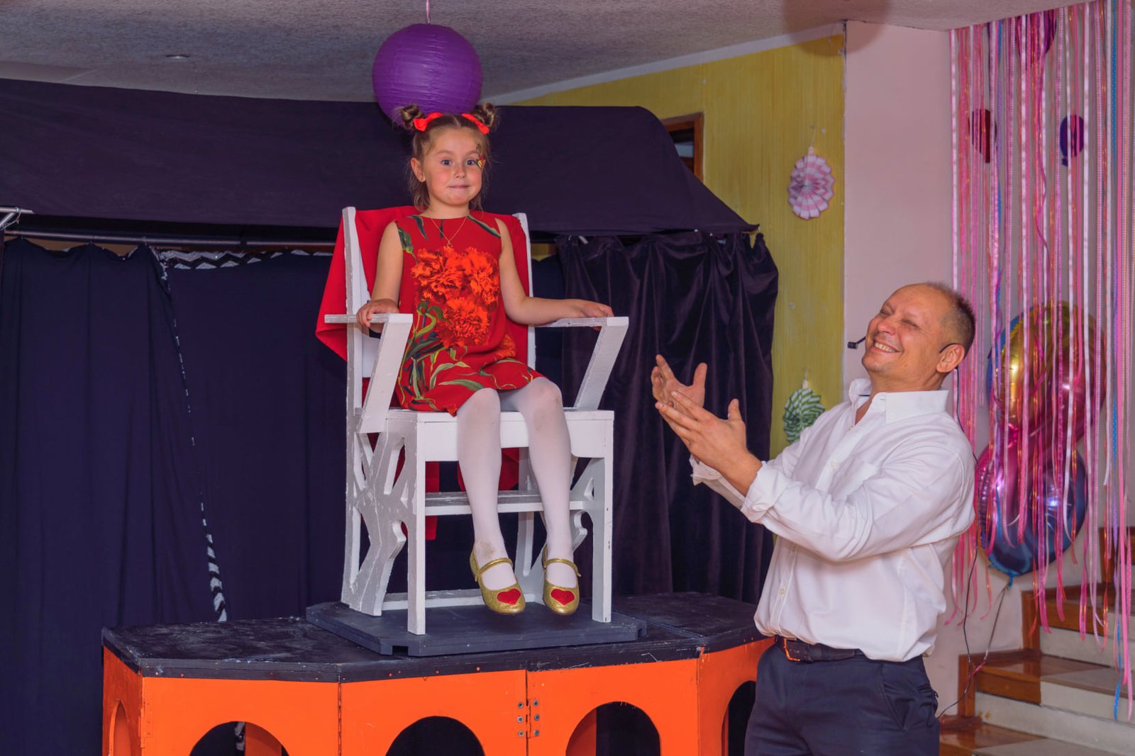 Niña levitando en una silla mientras el Mago Konstant la presenta ante los invitados